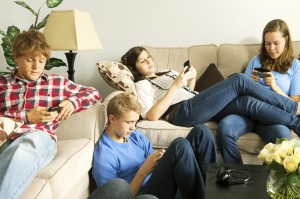 Teenagers texting on mobile phones in a home setting